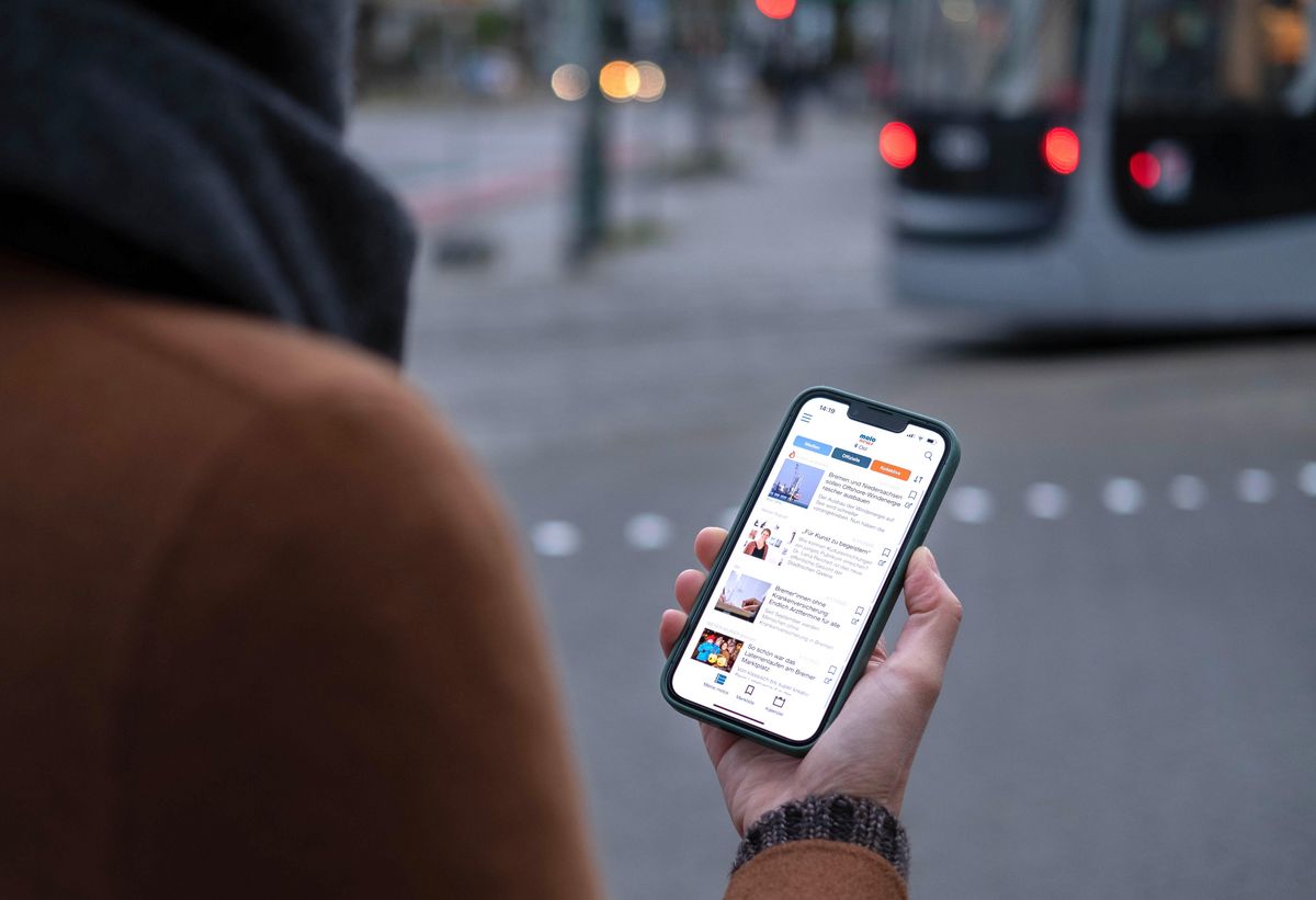 enlarge the image: Looking over a person's shoulder, you can see the screen of a smartphone with the Molo app open. The person is standing in an urban environment